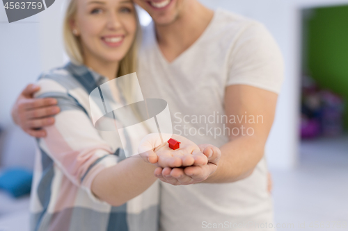 Image of couple showing small red house in hands