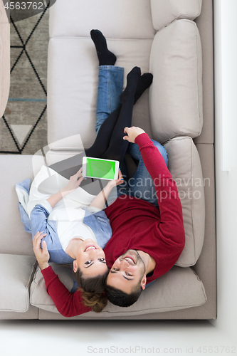 Image of couple relaxing at  home with tablet computers