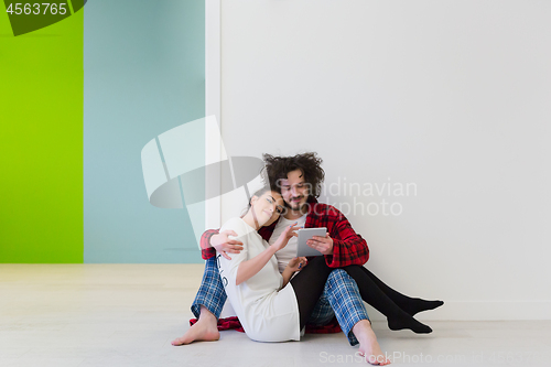 Image of Young Couple using digital tablet on the floor