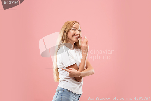 Image of The young woman whispering a secret behind her hand