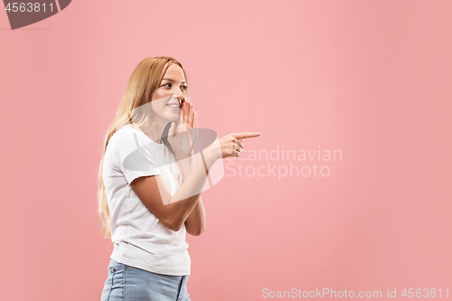 Image of The young woman whispering a secret behind her hand