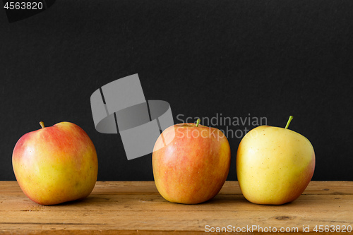Image of black background three apples wooden table
