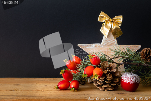 Image of wooden Star with twig pine cone and rose hip background