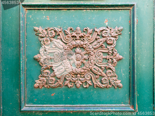 Image of rusty ornamental decoration at a green door in Italy