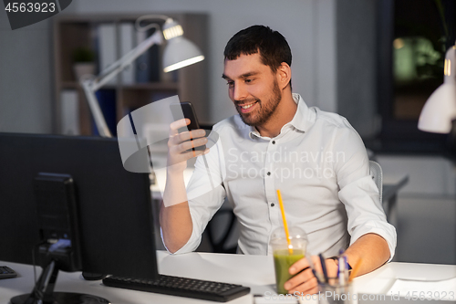 Image of businessman with smartphone at night office