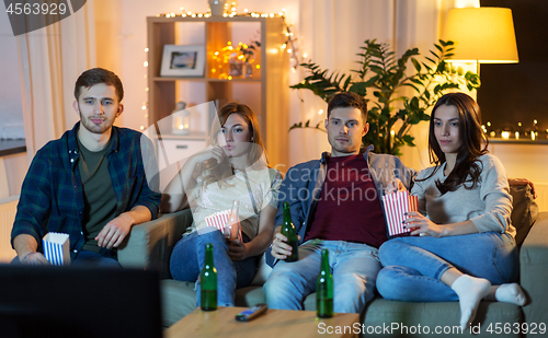 Image of friends with beer and popcorn watching tv at home