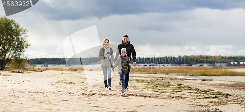 Image of happy family walking along autumn beach