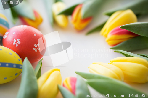 Image of close up of colored easter eggs and tulip flowers