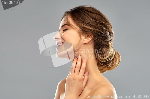 Image of smiling young woman touching her neck