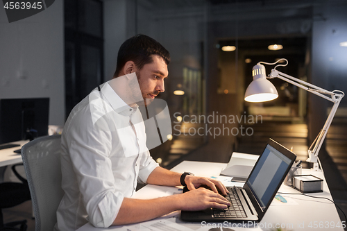 Image of businessman with laptop working at night office