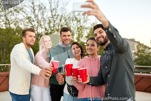 Image of friends with drinks taking selfie at rooftop party