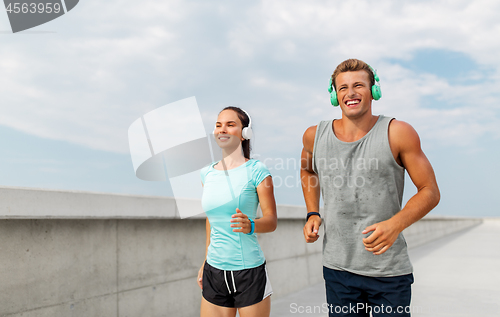 Image of couple with headphones running outdoors