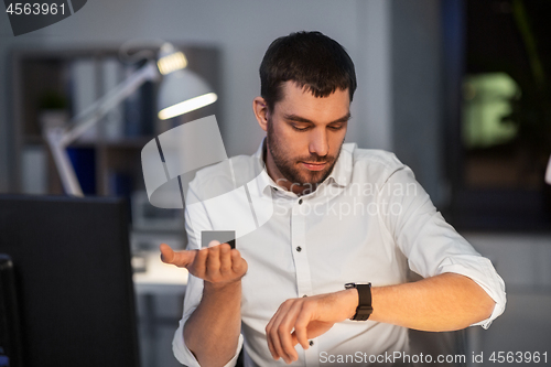 Image of businessman using smart speaker at night office