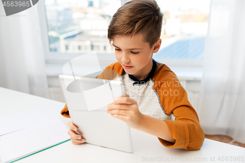 Image of student boy with tablet pc and notebook at home