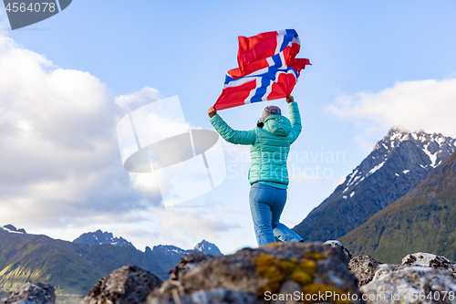 Image of Woman with a waving flag of Norway on the background of nature