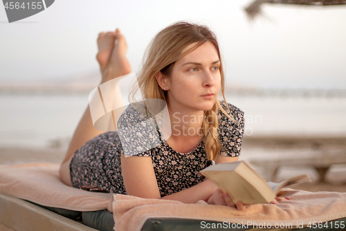 Image of Woman reading book on the beach