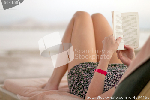 Image of Woman reading book on the beach