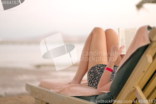 Image of Woman reading book on the beach
