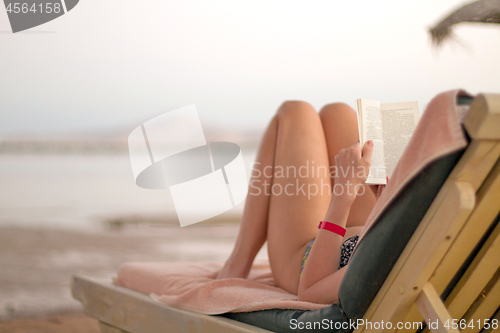 Image of Woman reading book on the beach