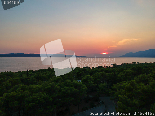 Image of An aerial view from drone to the trees and sunset over sea