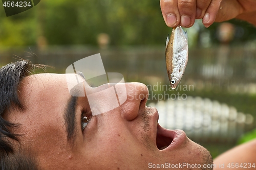 Image of Holding a very small fish above open mouth