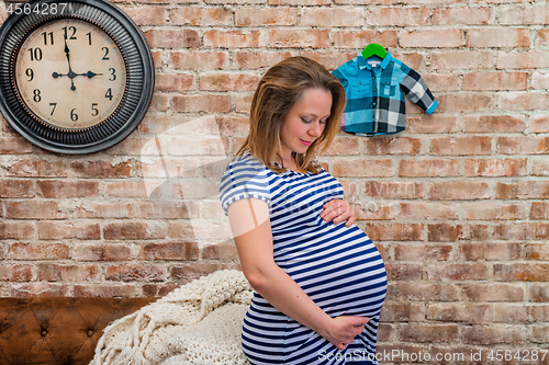 Image of Beautiful pregnant woman sitting near wall