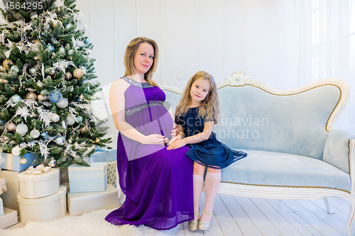 Image of Beautiful pregnant woman in ultra violet dress sitting with doughter