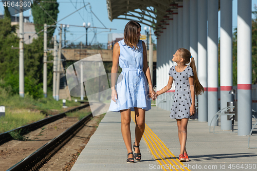 Image of Young beautiful girl and teenage daughter walk on the empty platform of the train station