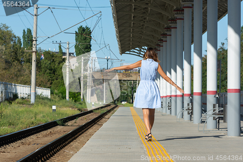 Image of Young beautiful girl goes on the platform holding her arms outstretched to the side