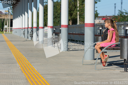 Image of Girl waiting for a train on the empty platform of the railway station