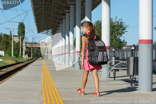 Image of Eight-year-old girl walks on the empty platform of the railway station