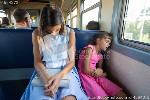 Image of Tired mother and daughter sleep soundly in an electric train