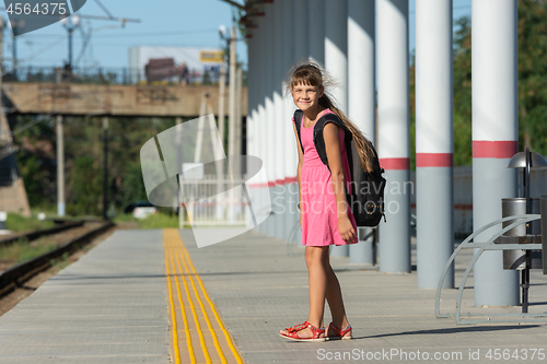 Image of The eight-year-old girl on the platform of the train station looked funny in the frame