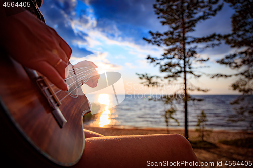 Image of Woman at sunset holding a ukulele