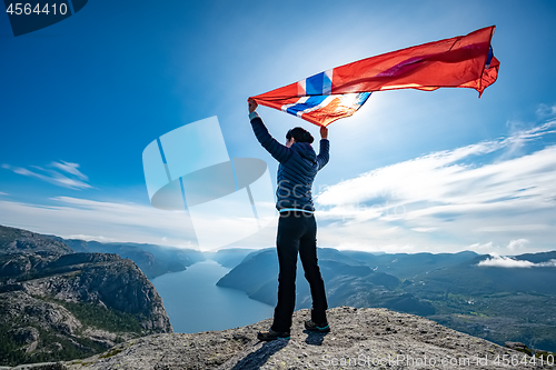 Image of Woman with a waving flag of Norway on the background of nature