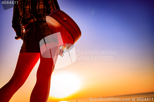 Image of Woman at sunset holding a ukulele