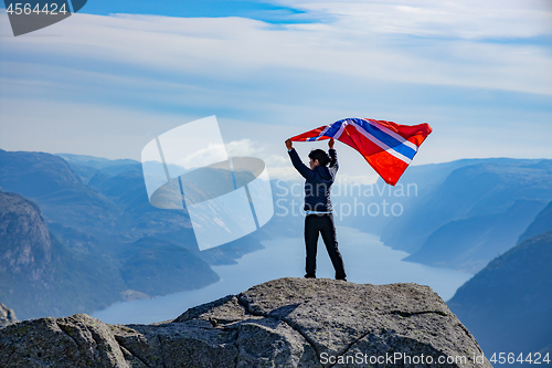 Image of Woman with a waving flag of Norway on the background of nature