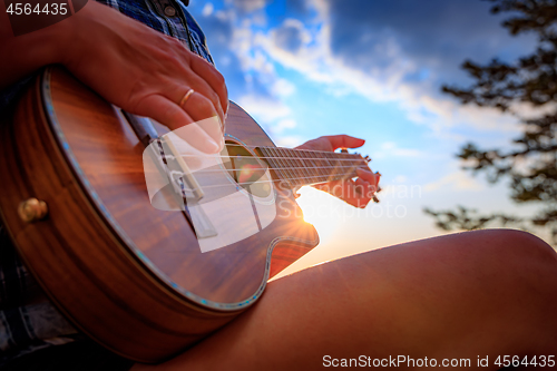 Image of Woman at sunset holding a ukulele