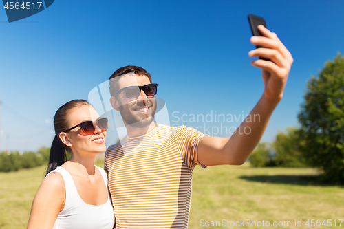 Image of happy couple taking selfie by smartphone in summer