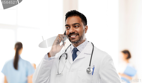 Image of smiling indian male doctor calling on smartphone