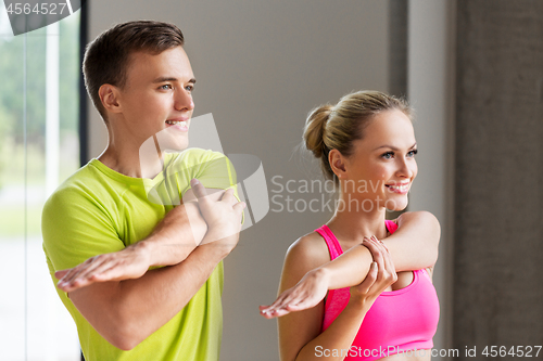 Image of smiling man and woman exercising in gym