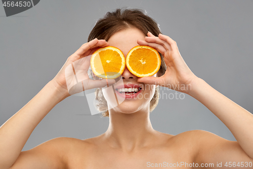 Image of smiling woman with oranges over grey background