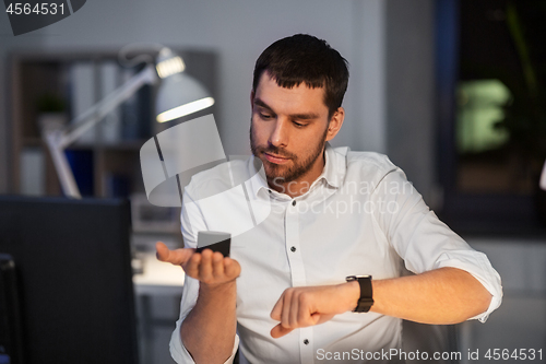 Image of businessman using smart speaker at night office