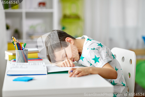 Image of tired student boy sleeping on table at home