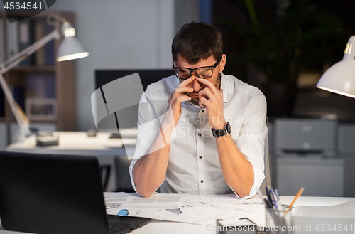 Image of tired businessman working at night office