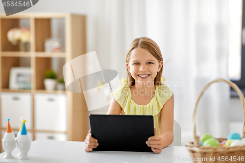 Image of happy girl with tablet pc and easter eggs at home