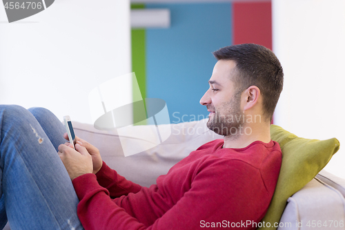 Image of young man using a mobile phone  at home