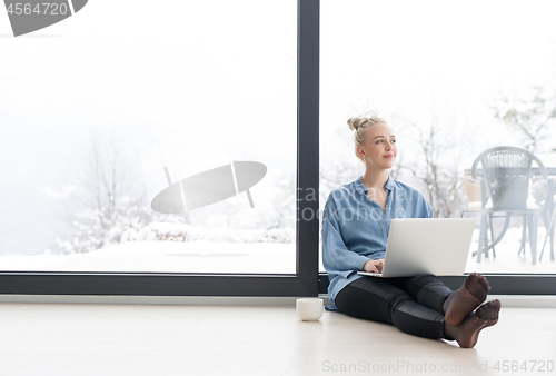 Image of woman drinking coffee and using laptop at home