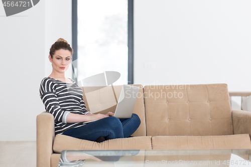 Image of young woman on sofa at home websurfing