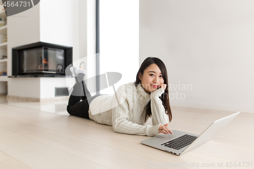 Image of young Asian woman using laptop on the floor